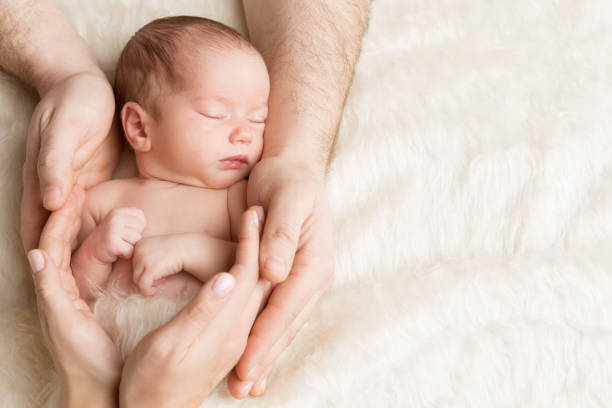 Newborn Baby in Family Hands, Sleeping New Born Kid, Parents Care Newborn Baby in Family Hands, Sleeping New Born Kid, Parents Care and Protection Concept babyhood photos stock pictures, royalty-free photos & images