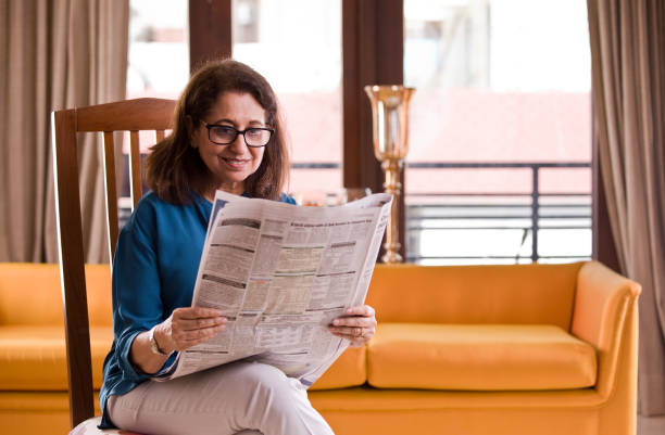 istock Senior woman reading newspaper at home 1150120877