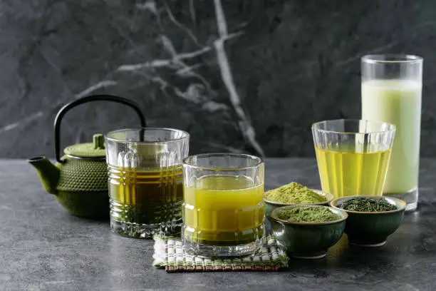 Variety of matcha tea served with sencha and matcha powder over dark wooden background