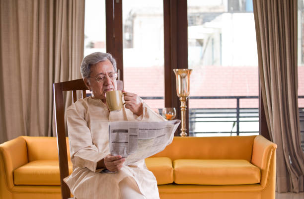 自宅でコーヒーを飲んで新聞を読む老人 - senior adult relaxation sofa reading ストックフォトと画像