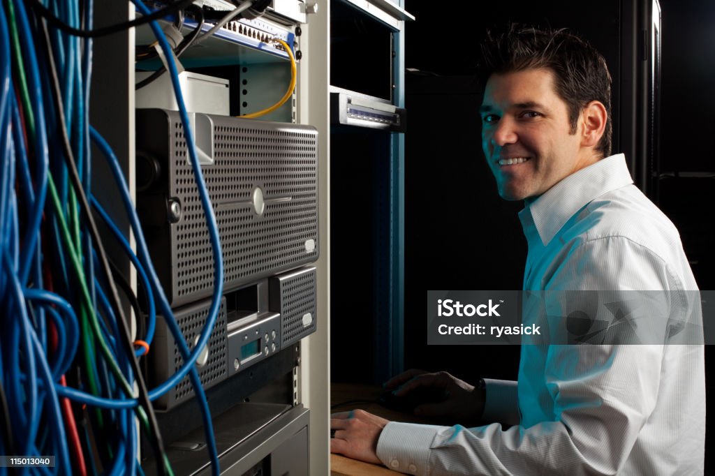 Ce technicien regardant la caméra dans la salle d'équipement sur ordinateur - Photo de Employé de l'administration libre de droits