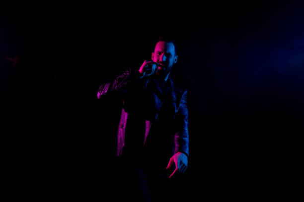 istock Handsome man singing in black background with gel lighting 1150134566