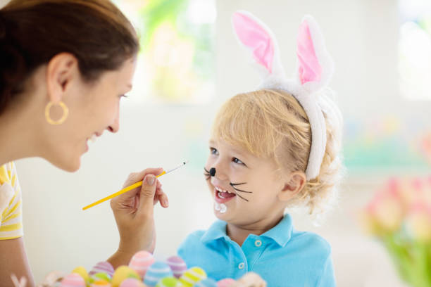 mutter und kinder, familie färbt ostereier. - bemalte gesichter stock-fotos und bilder