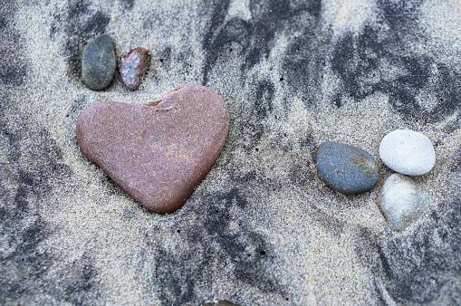 red stone heart, sea stone in the shape of a heart on the sand