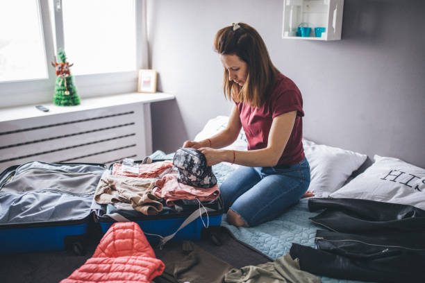 istock Woman sitting on her bed and packing suitcase 1150135697