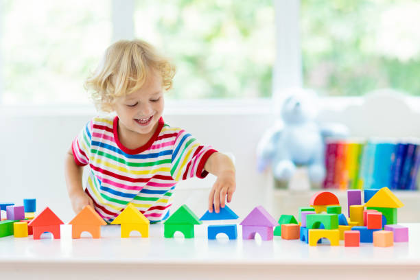 Kids toys. Child building tower of toy blocks. Kid playing with colorful toy blocks. Little boy building tower of block toys. Educational and creative toys and games for young children. Baby in white bedroom with rainbow bricks. Child at home. preschool student stock pictures, royalty-free photos & images