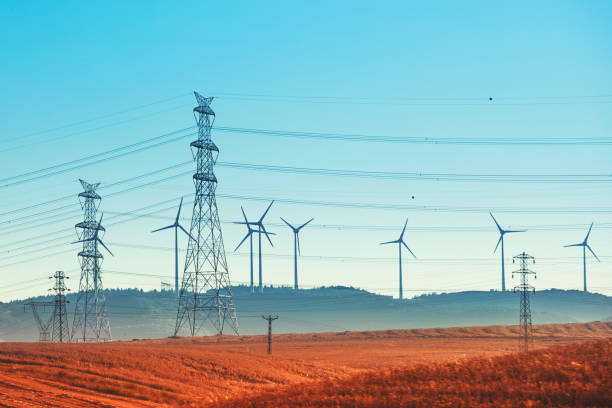 Windmill power generator on grassland, Electric Power Lines and Transmission Tower stock photo