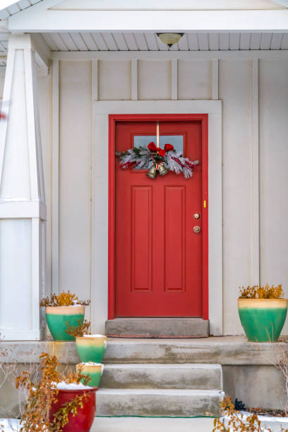 istock Front door with glass panel and holiday decoration against a ribbed white wall 1150145231