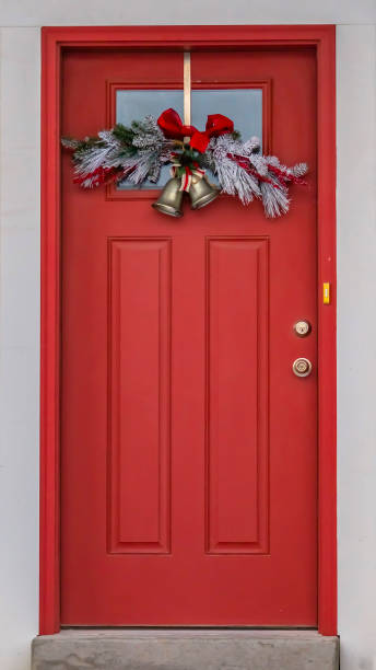 istock Vertical Front door with glass panel and holiday decoration against a ribbed white wall 1150145268