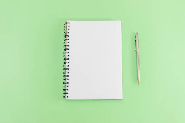 istock White notepad with steel pen on a green background. Office table, minimal composition. Copy space. 1150145357