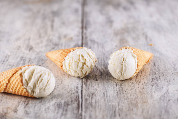 istock Vanilla ice cream with cone on wooden background background 1150145521