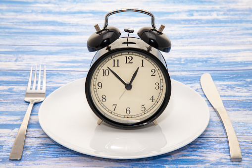 An alarm clock on a dinner plate - concept image