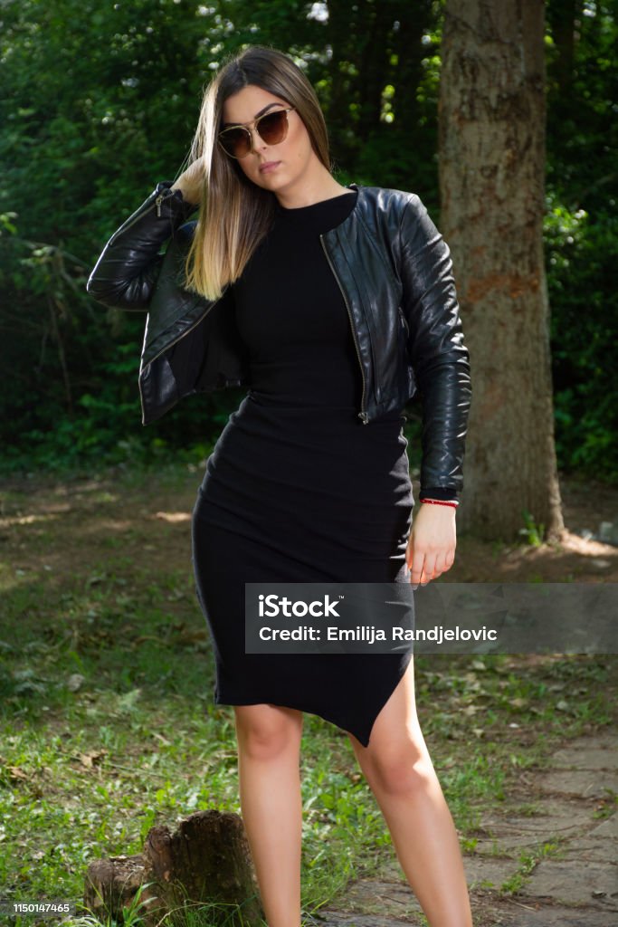 Una Hermosa Mujer Modelo De Moda En Vestido Negro Y Chaqueta De Cuero Y  Gafas De Sol Posando En La Naturaleza En Un Soleado Día De Primavera Foto  de stock y más