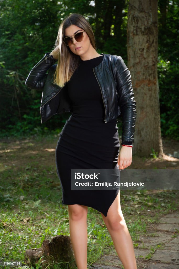 Una Hermosa Mujer Modelo De Moda En Vestido Negro Y Chaqueta De Cuero Y Gafas De Sol Posando En La Naturaleza En Un Soleado Día De Primavera Foto de stock y más Una Hermosa Mujer Modelo De Moda En Vestido Negro Y Chaqueta De Cuero Y Gafas De Sol Posando En La Naturaleza En Un Soleado Día De Primavera Foto de stock y más