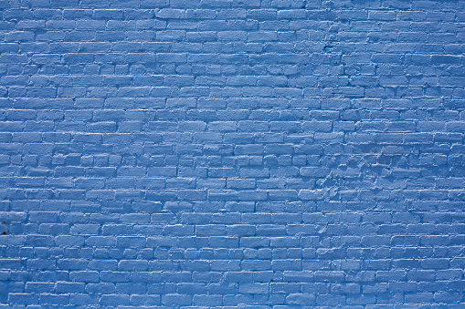 Section of an old brick wall freshly painted blue.