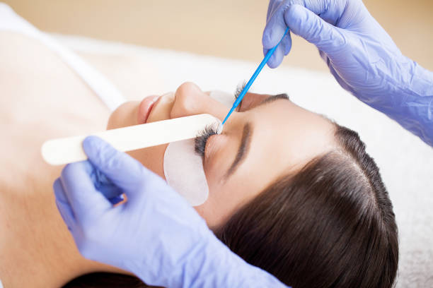 istock Eyelashes extensions. Fake Eyelashes. Eyelash Extension Procedure. Professional stylist lengthening female lashes. Master and a client in a beauty salon 1150163598