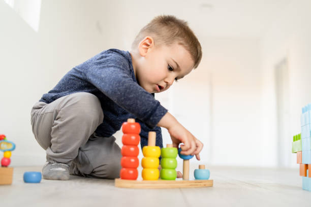 small boy playing with little wood toys at home on the floor learning colors and counting - construction material material brick building activity imagens e fotografias de stock