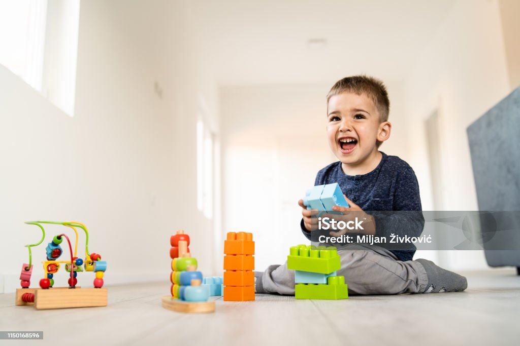 Kleiner Junge spielt mit kleinen Backstein-Spielzeug zu Hause auf dem Boden lächelnd - Lizenzfrei Boden Stock-Foto