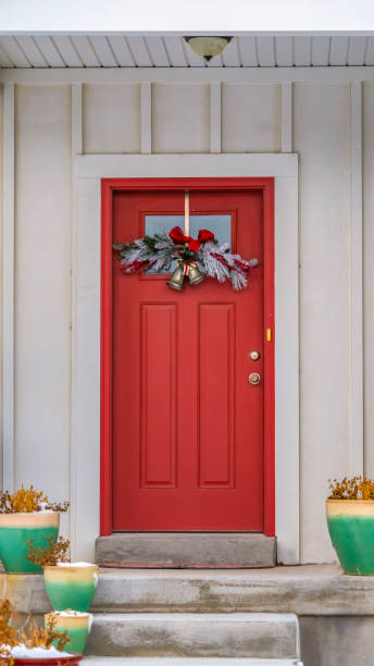 istock Vertical Front door with glass panel and holiday decoration against a ribbed white wall 1150186133