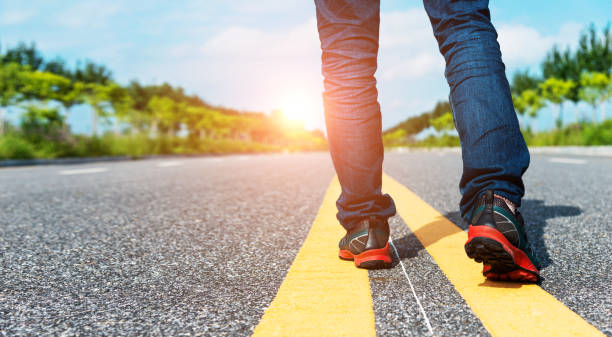 istock Man legs walking on asphalt road 1150191413