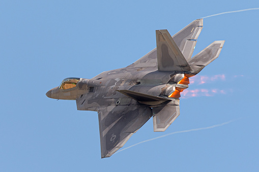 F-22 Raptor in a  high G maneuver, with condensation trails forming  at the wings tip and afterburners on