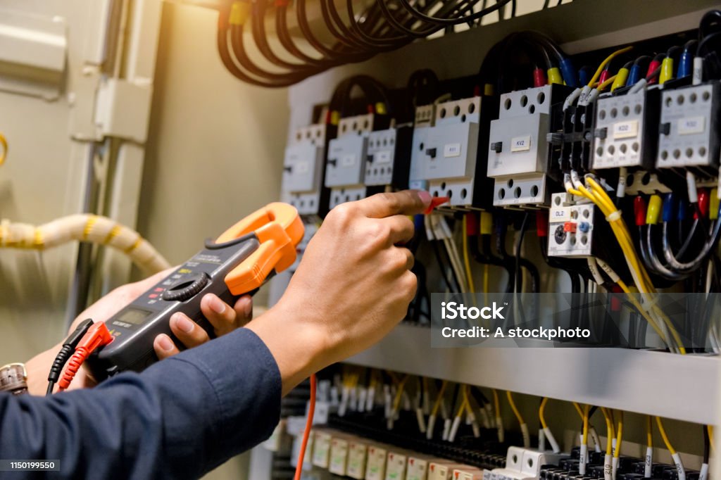 Electrician engineer work  tester measuring  voltage and current of power electric line in electical cabinet control. Electricity Stock Photo