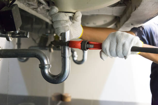 Plumber fixing white sink pipe with adjustable wrench. stock photo