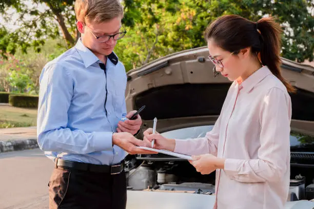 Insurance agent writing document on clipboard examining car after accident, Insurance concept