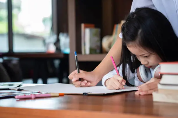 Photo of cute girl smiled and sitdown to drawing a book in the library, children concept, education concept