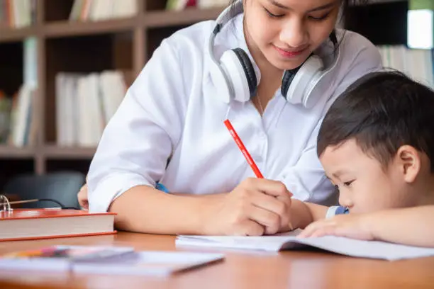 Photo of cute girl smiled and sitdown to drawing a book in the library, children concept, education concept