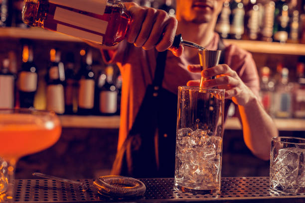 istock Barman wearing uniform pouring alcohol into glass with ice 1150202393