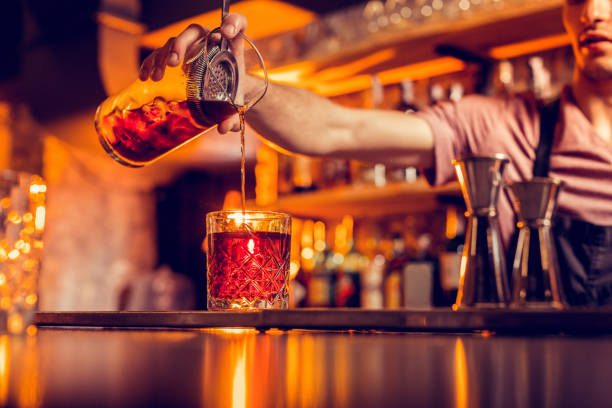 Barman pouring cocktail into glass while working at night