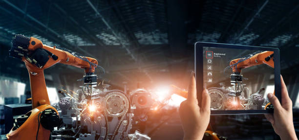 istock Augmented reality industry concept. Hand holding digital tablet use AR application to check and control welding robotics automatic arms machine in intelligent factory automotive industrial with monitoring system software. Digital manufacturing operation. 1150204838