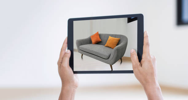 AR augmented reality. Hand holding digital tablet, AR application, simulate sofa furniture and and interior design real room background, modern technology.