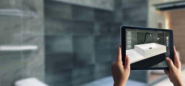 Planificación del baño de realidad aumentada. Vajilla sanitaria. Mano sosteniendo la tableta digital en el fondo del hogar real, aplicación AR. Una nueva forma de experimentar los productos. photo