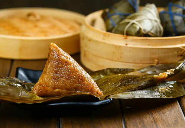 Photo of duanwu festival rice dumplings zongzi and bamboo steamer on wooden table