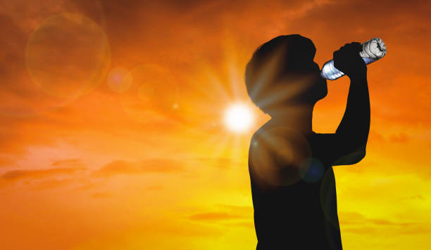 Silhouette man is drinking water bottle on hot weather background with summer season. High temperature and heat wave concept. Silhouette man is drinking water bottle on hot weather background with summer season. High temperature and heat wave concept. heat wave photos stock pictures, royalty-free photos & images