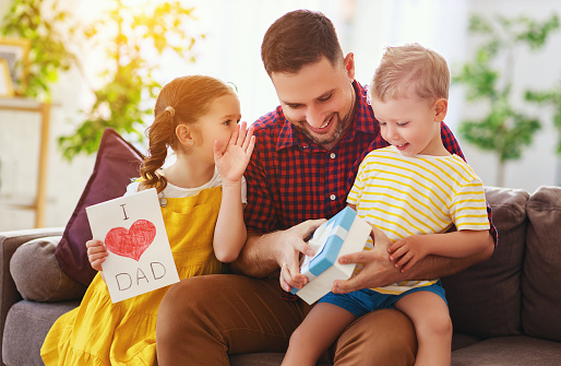 Happy father's day! Children congratulates dad and gives  him a gift and postcard