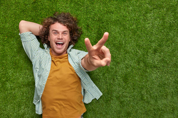 Man on grass showing V sign