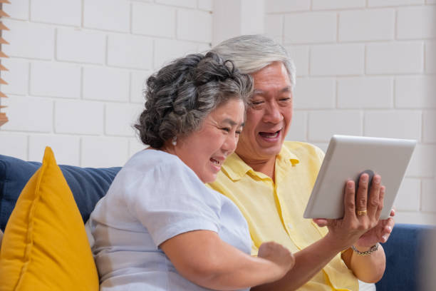 asian senior couple use tablet video call and talk to grandchild - ipad senior adult facebook sofa imagens e fotografias de stock