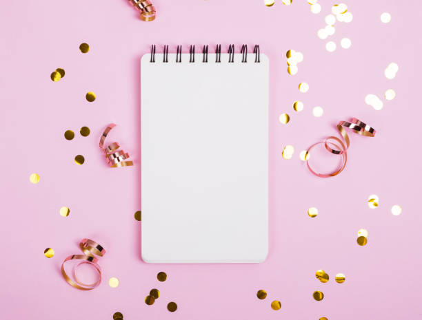 istock Notepad on the pink background with golden confetti, glitter and other festive decor. 1150243717