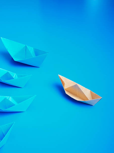 istock Single light brown origami paper boat with blue boats group 1150244251