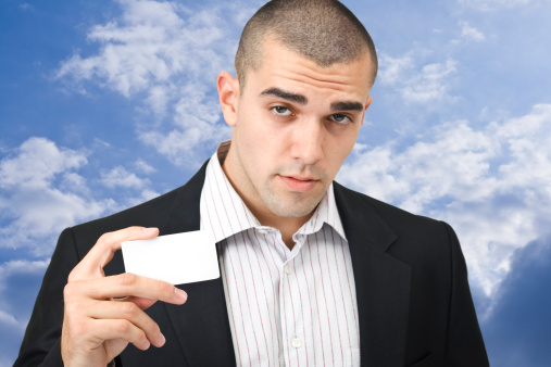 Young man showing card on sky background - focus is on hand with card