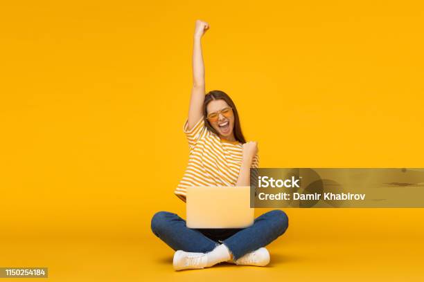 She Is A Winner Excited Young Female With Laptop Isolated On Yellow Background Stock Photo - Download Image Now
