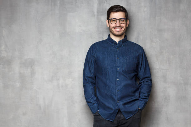 istock Young handsome male smiling and feeling confident, standing against textured wall background, copy space on left 1150254228