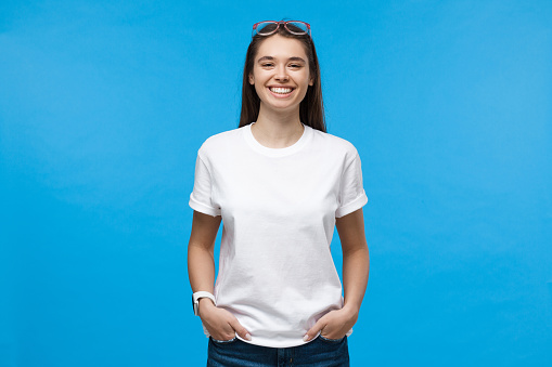 Young smiling female wearing white t-shirt, isolated on blue background
