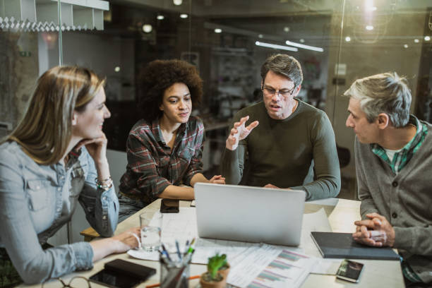 istock Group of casual business people talking while using laptop in the office. 1150256095