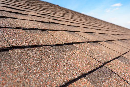 Close up photo of asphalt shingles layer on top of roof on new house under construction