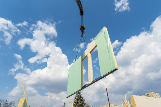 istock Process of construction new and modern modular house from composite sip panels. Low view angle photo of crane with sip panel against sky and blue background 1150256311