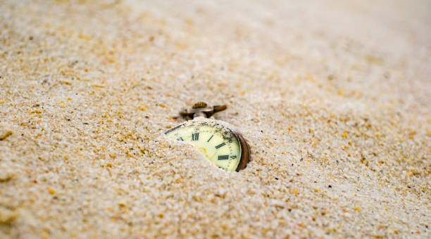 sand der zeit. antike verrottete taschenuhr teilweise im sand vergraben. - lost in time stock-fotos und bilder